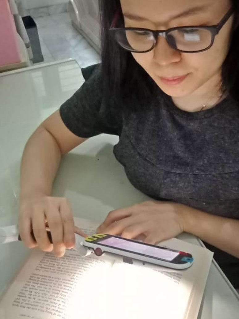 Mellisa Chian tengah membaca menggunakan alat bantu pembesaran 2